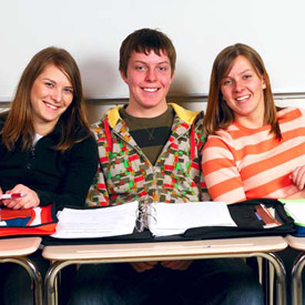 three high school students with binders open at desks