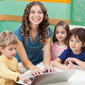 teacher at laptop computer with young students